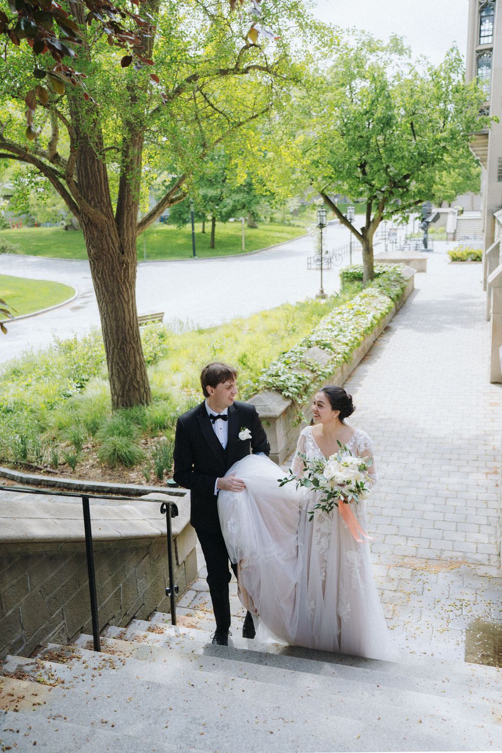 Couple walking down church steps surrounded by spring greenery on their wedding day.