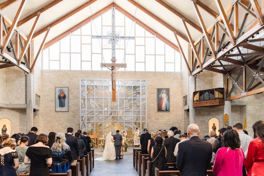 Wedding guests gather inside rustic wooden beam church sanctuary during a daytime ceremony.