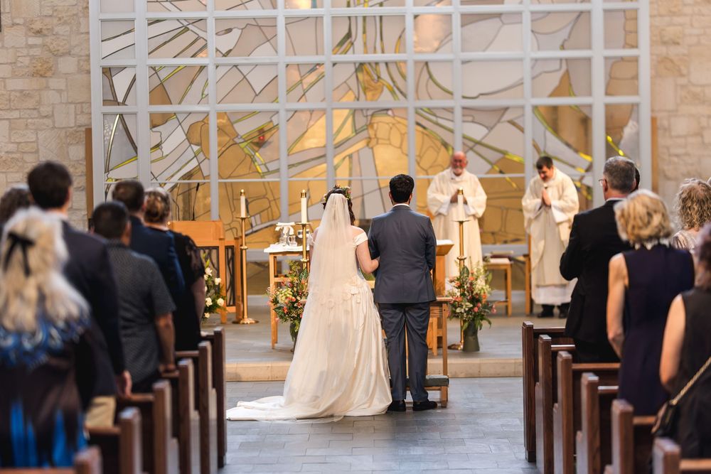 A wedding ceremony takes place in a modern church with white geometric architecture and glowing golden lighting.