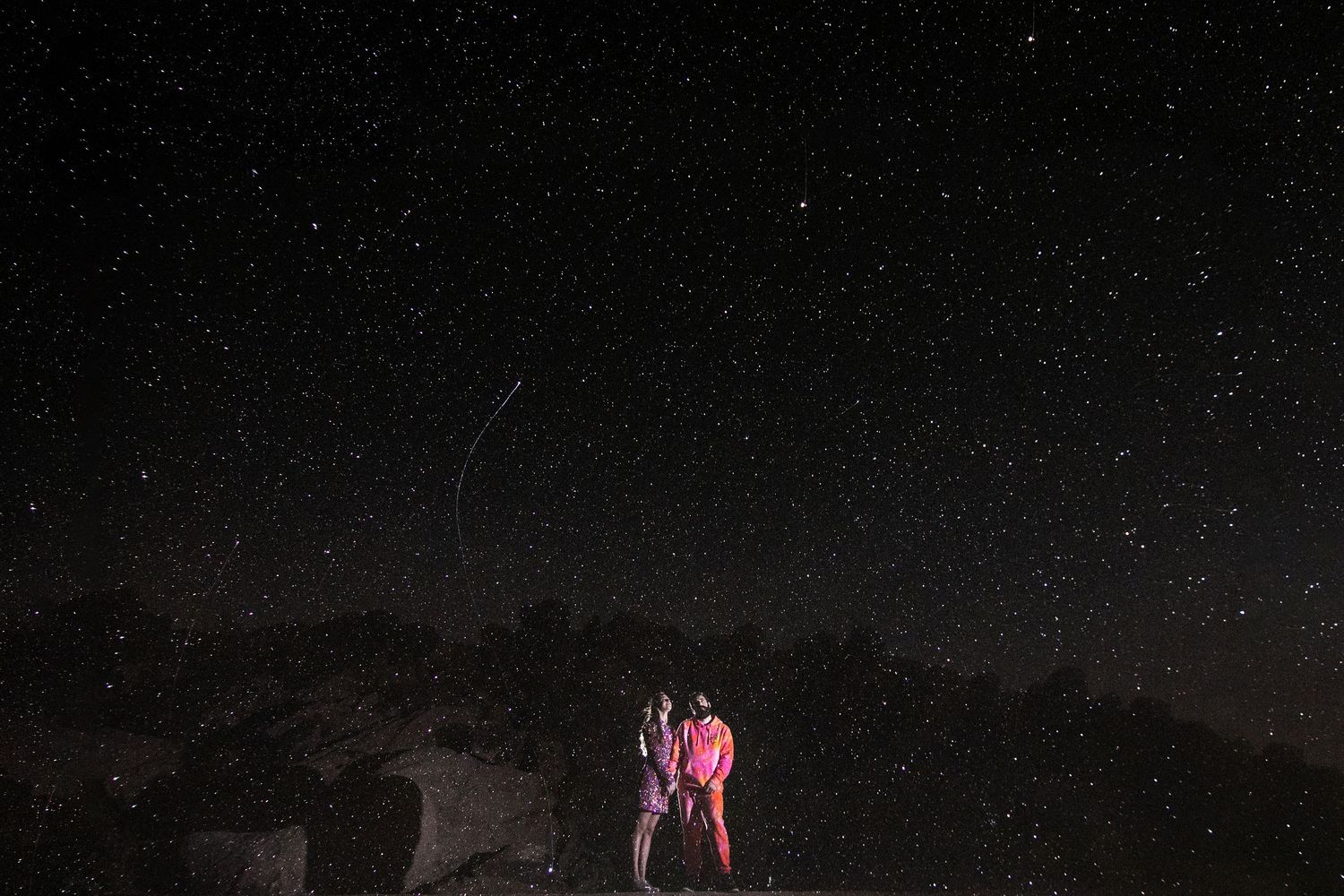 Mike Rosenstein & lindsay garrison pose under a starry sky in joshua tree california after their wedding night with a shooting star overhead