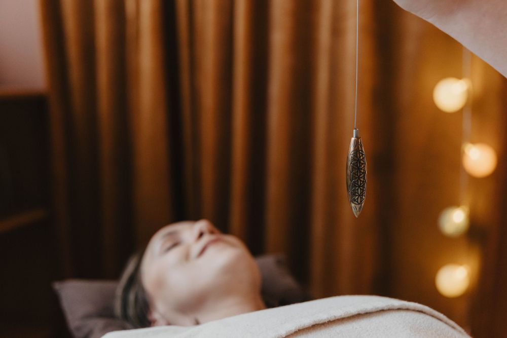 kvinna under behandling med en pendel i healing
