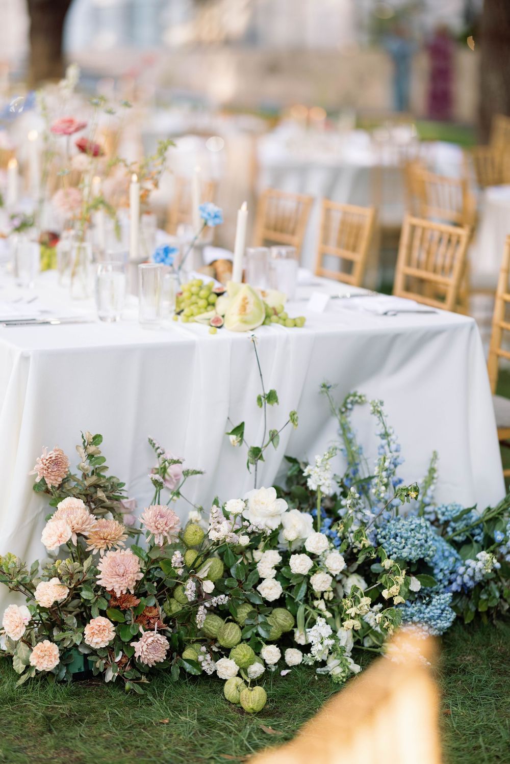 Elegant wedding table setting with soft pink and blue floral arrangements cascading down white linens.