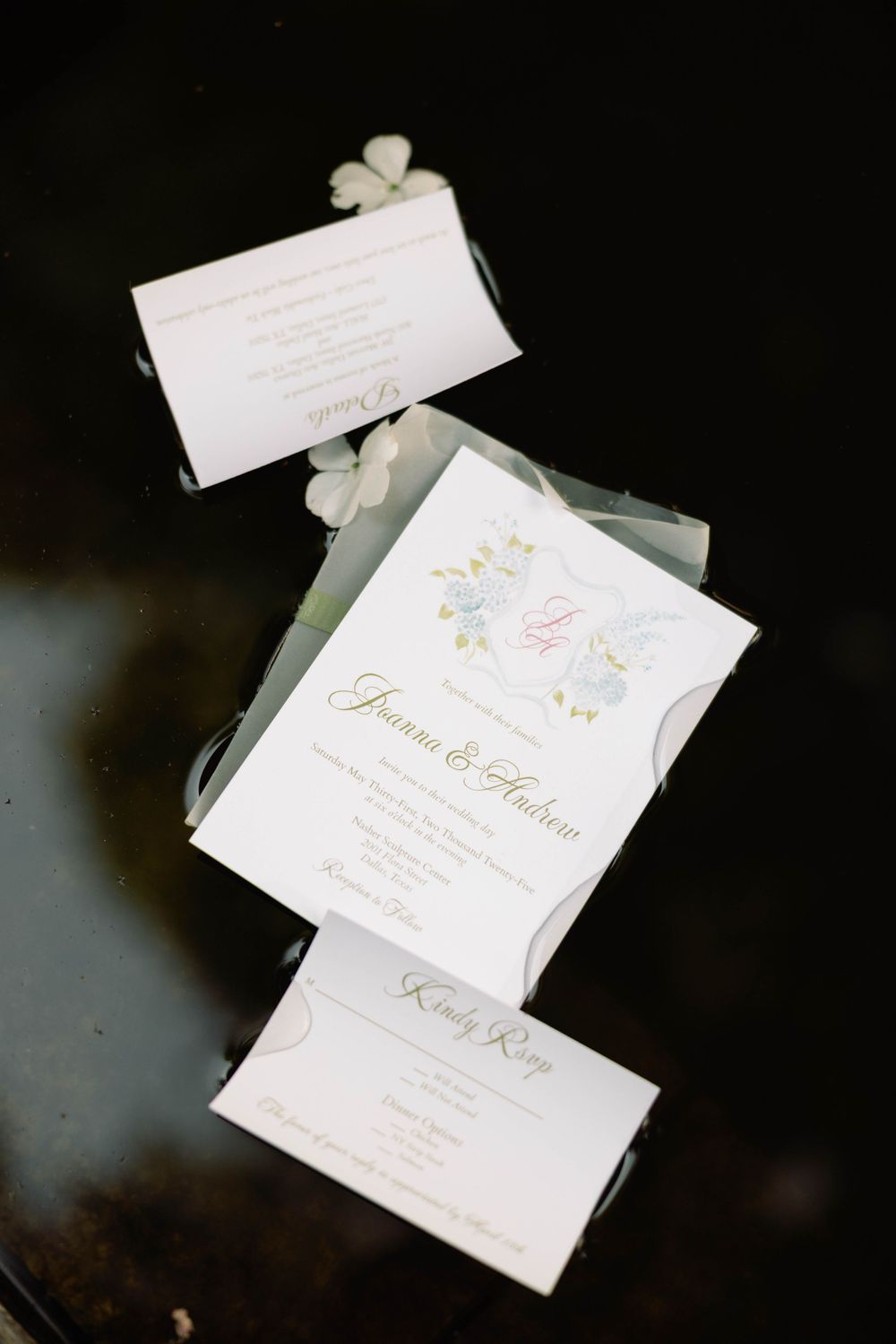 Wedding invitation cards with gold lettering scattered artistically on dark background.