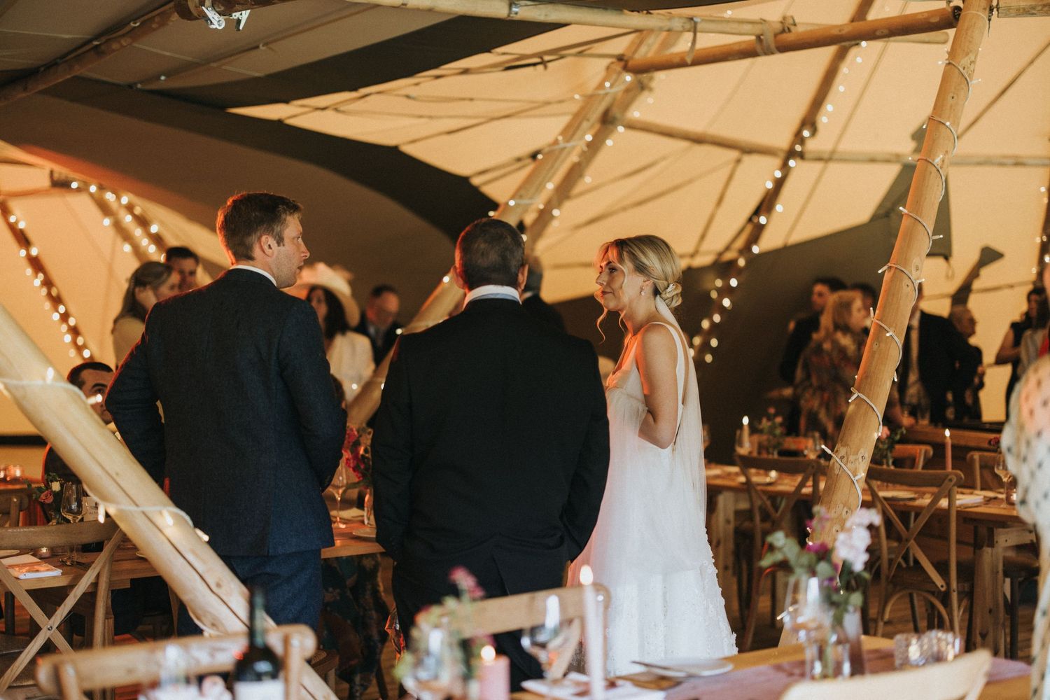 Wedding ceremony setup under a tent with string lights and wooden benches at Scrivelsby Walled Garden.