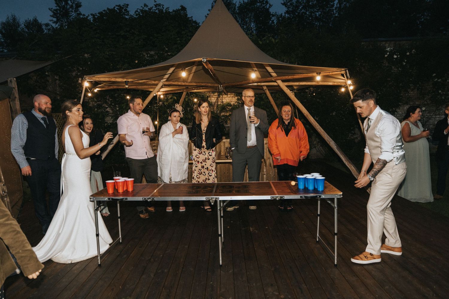 People enjoying beer ping at casual outdoor wedding reception under string lights at Scrivelsby Walled Garden.