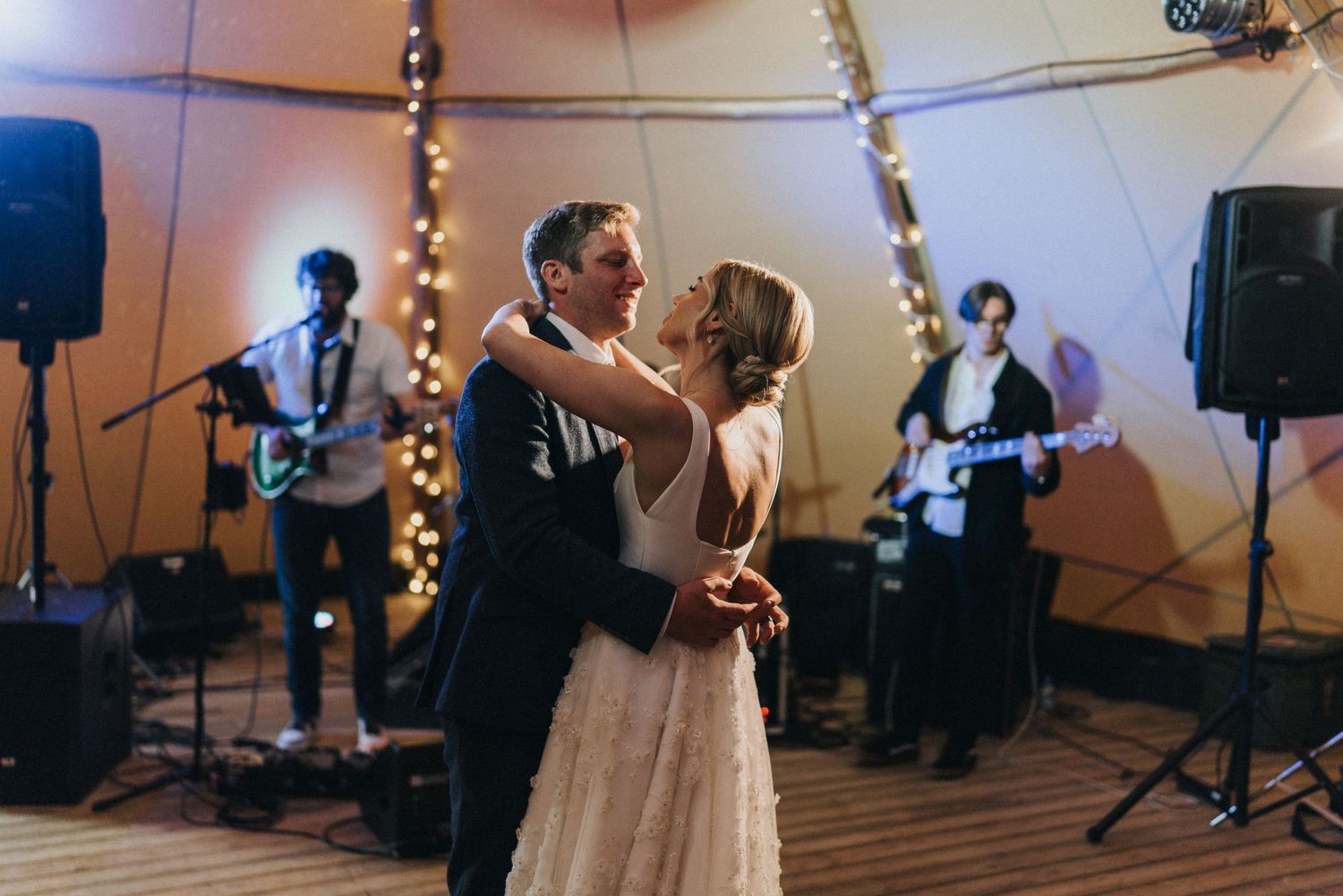 A couple shares their first dance at a wedding reception while a band plays in the background at Scrivelsby Walled Garden.
