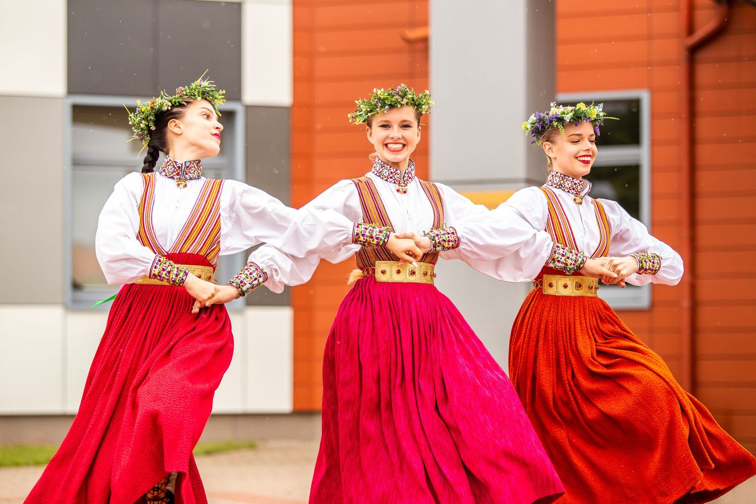 Traditional dancers in red skirts and white blouses performing outdoors.