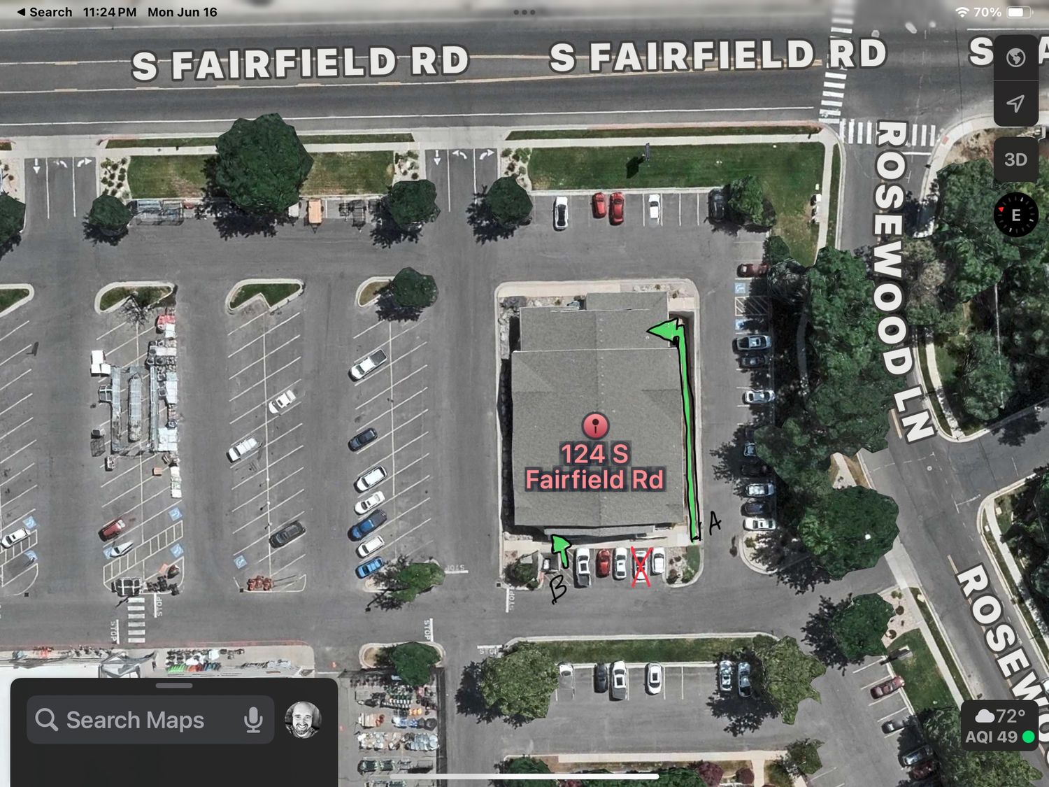 Aerial view of a commercial parking lot with businesses along S Fairfield Road showing parked cars and surrounding trees.
