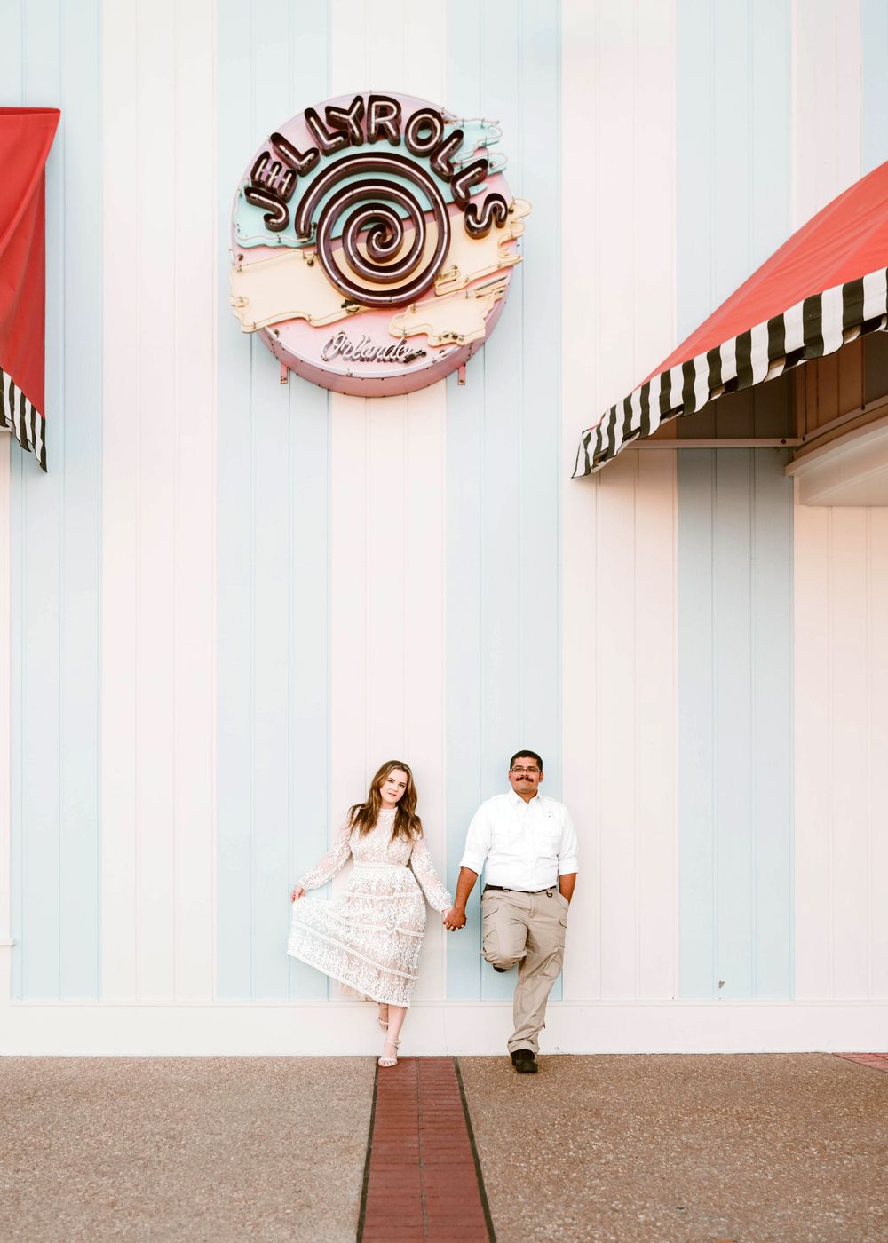 Gillian & Miles' anniversary photos at Disney Boardwalk. Gillian in white lace Ivy City Co dress, outside of Jelly Rolls. Cred: LexTakePix