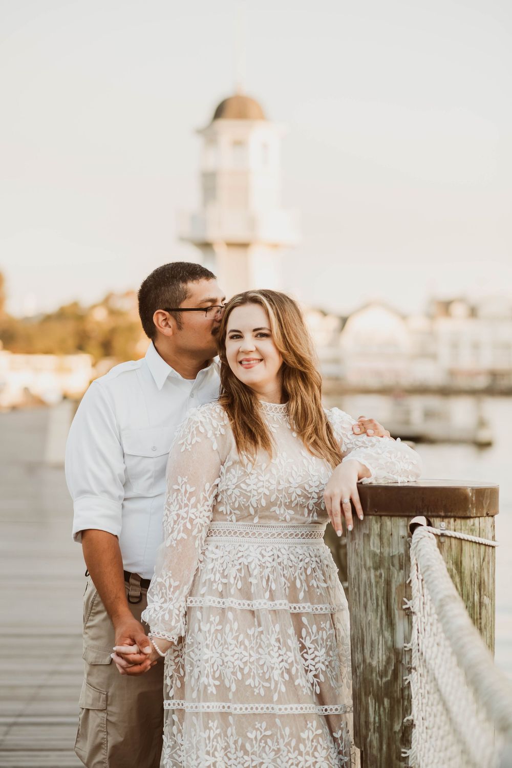 Gillian & Miles' anniversary photos at Disney Boardwalk. Gillian in white lace Ivy City Co dress, with Lighthouse in backCred: LexTakePix