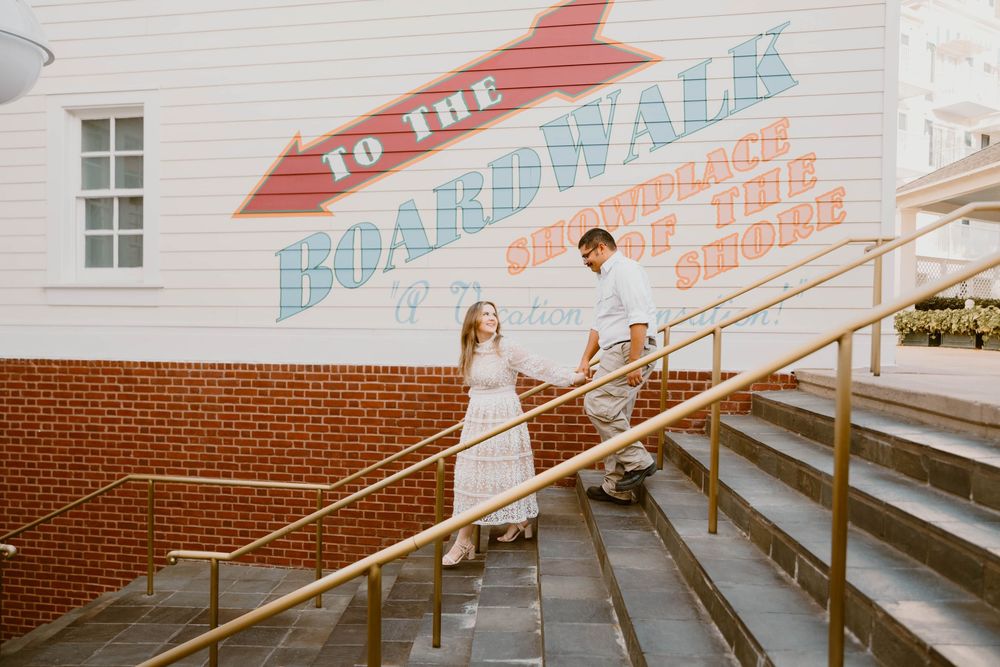 Gillian & Miles' anniversary photos at Disney Boardwalk. Gillian in white lace Ivy City Co dress, walking down stairs. Cred: LexTakePix