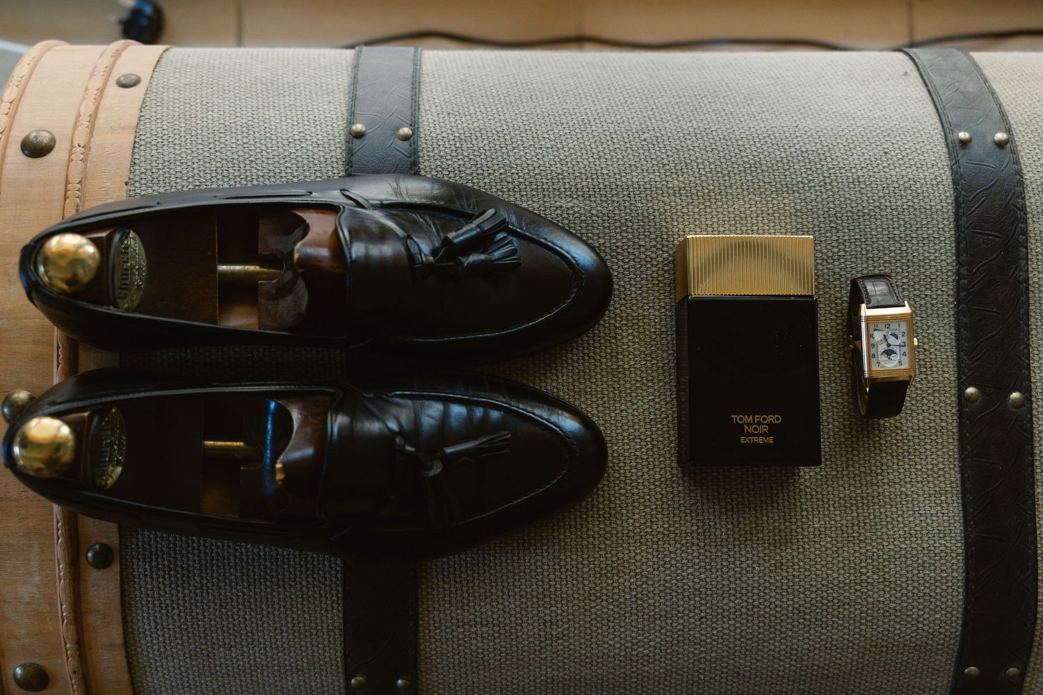 Leather dress shoes and boots displayed in a row on wooden shelving against a gray fabric background.