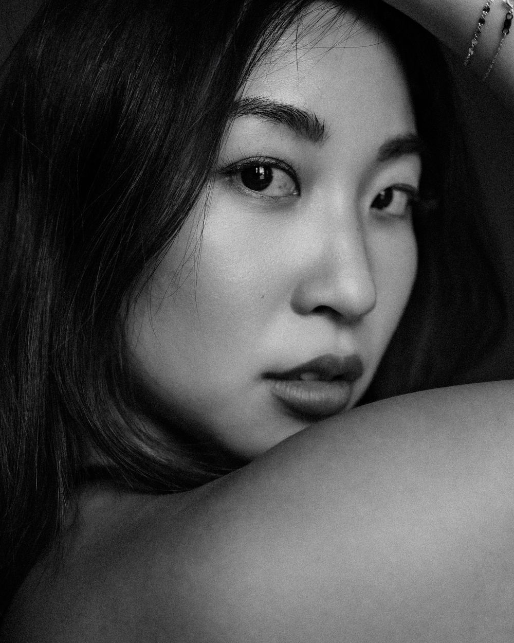 Close-up black and white portrait showing artistic composition with dramatic shadows and light.