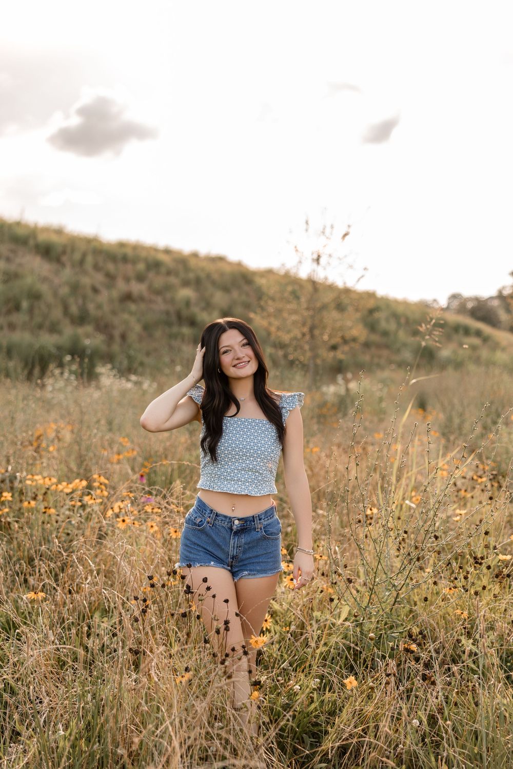 Candid outdoor photography in a field of golden wildflowers during sunset with casual summer attire.