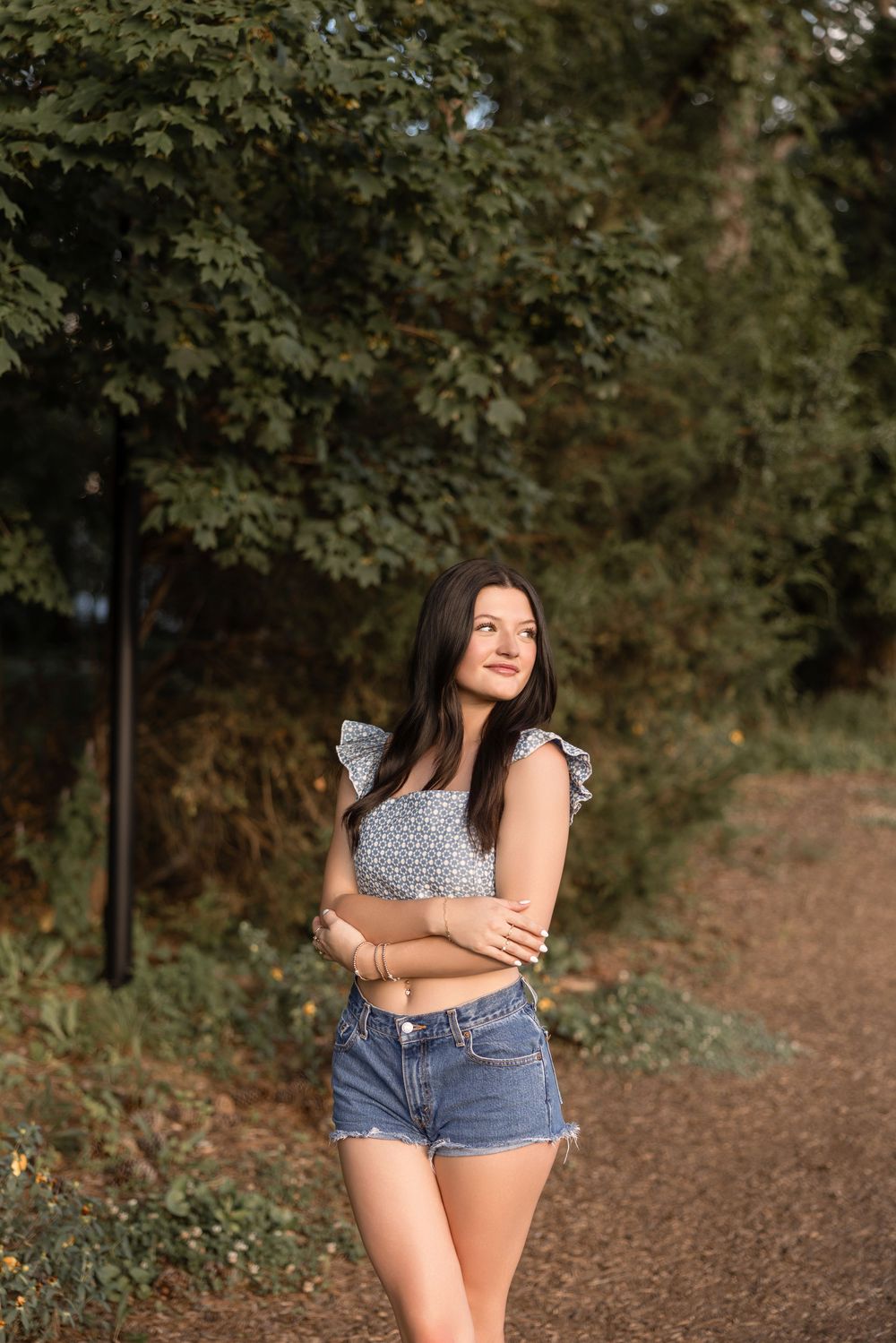 A casual summer portrait on a dirt path with green foliage in the background.