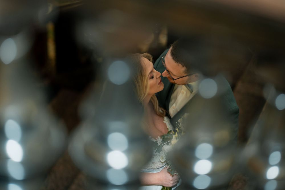 A romantic couple embraces in an intimate kiss framed by soft bokeh lights creating a dreamy atmosphere.