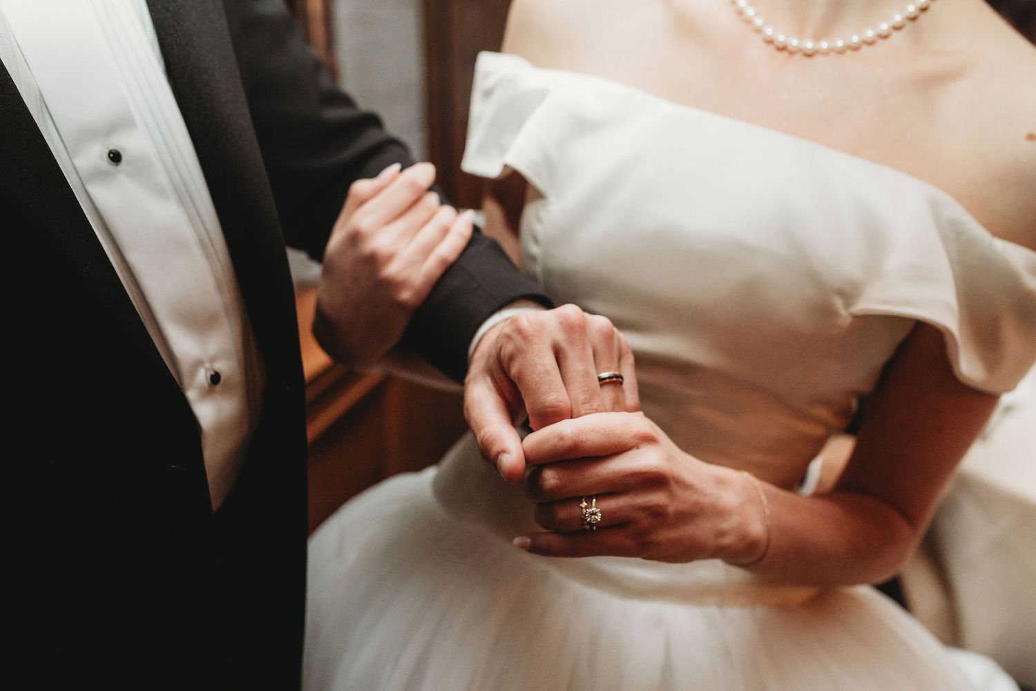 A bride in a white gown shows multiple angles of her hands texting on a mobile phone.