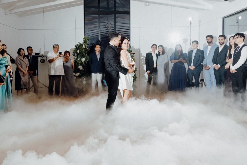 A couple shares their first dance on a fog-filled dance floor captured by Apertured Media Auckland Wedding Photographer.
