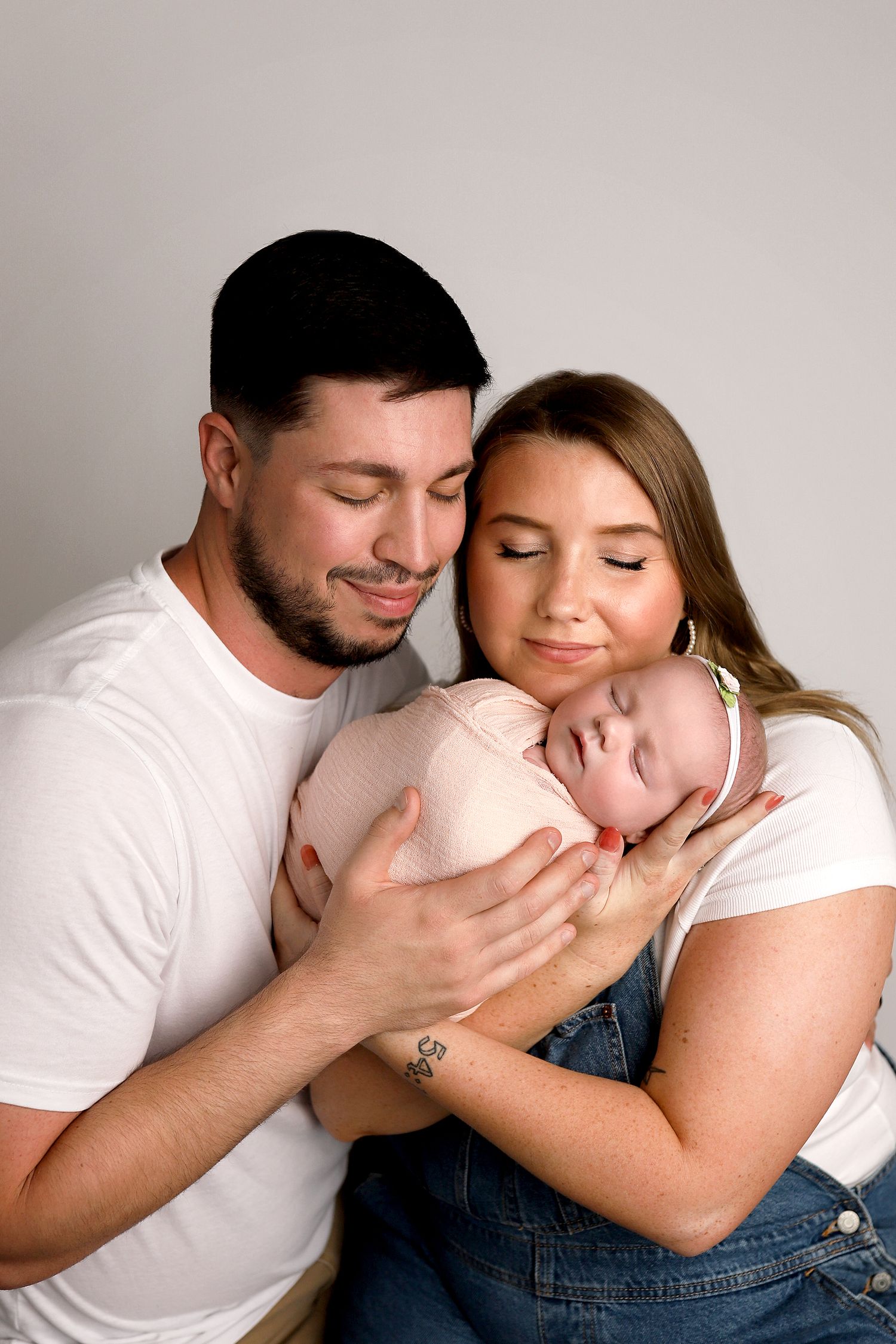 Family sharing tender moment together against neutral grey background. Utah newborn photographer. Orem baby photography