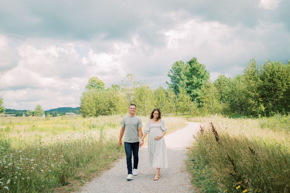 Couple walking together on a countryside path surrounded by wildflowers and greenery.