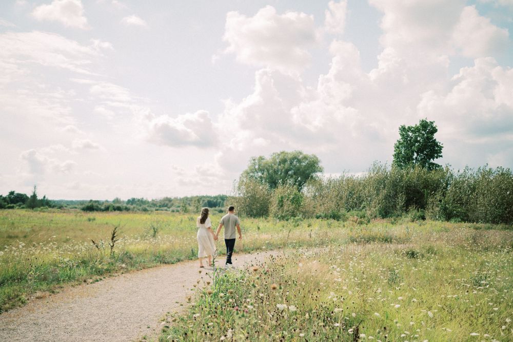 Scenic countryside path with couple walking among wildflowers and natural landscape.