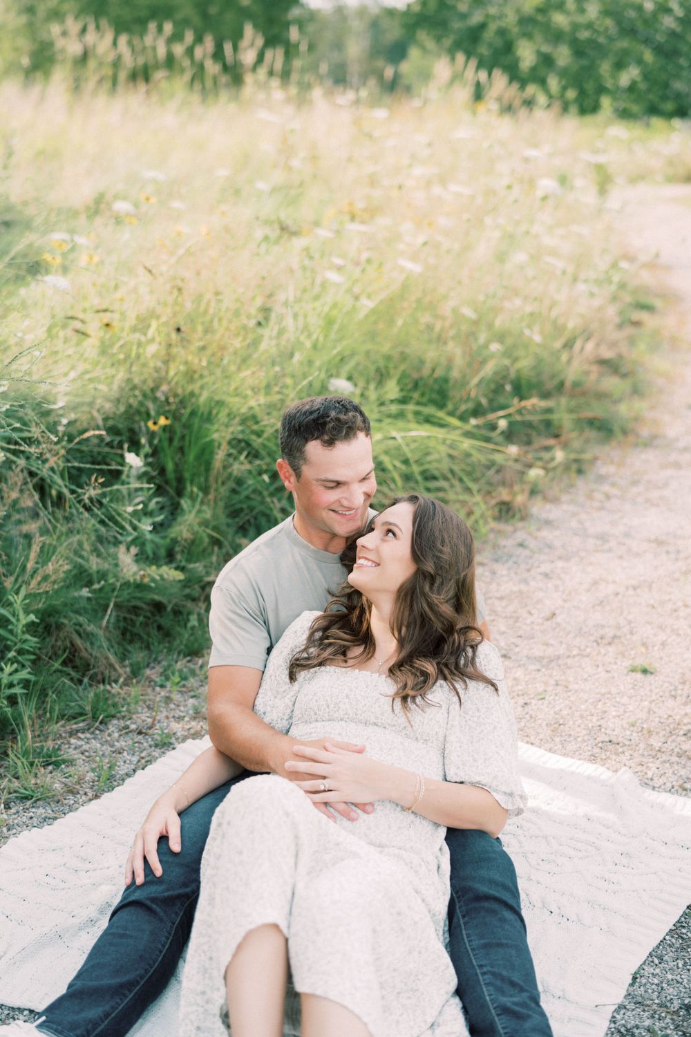 Couple shares loving moment while relaxing on blanket in summer meadow.