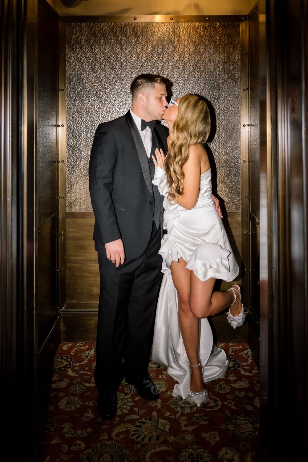 Romantic moment captured in elevator doorway with formal evening attire.