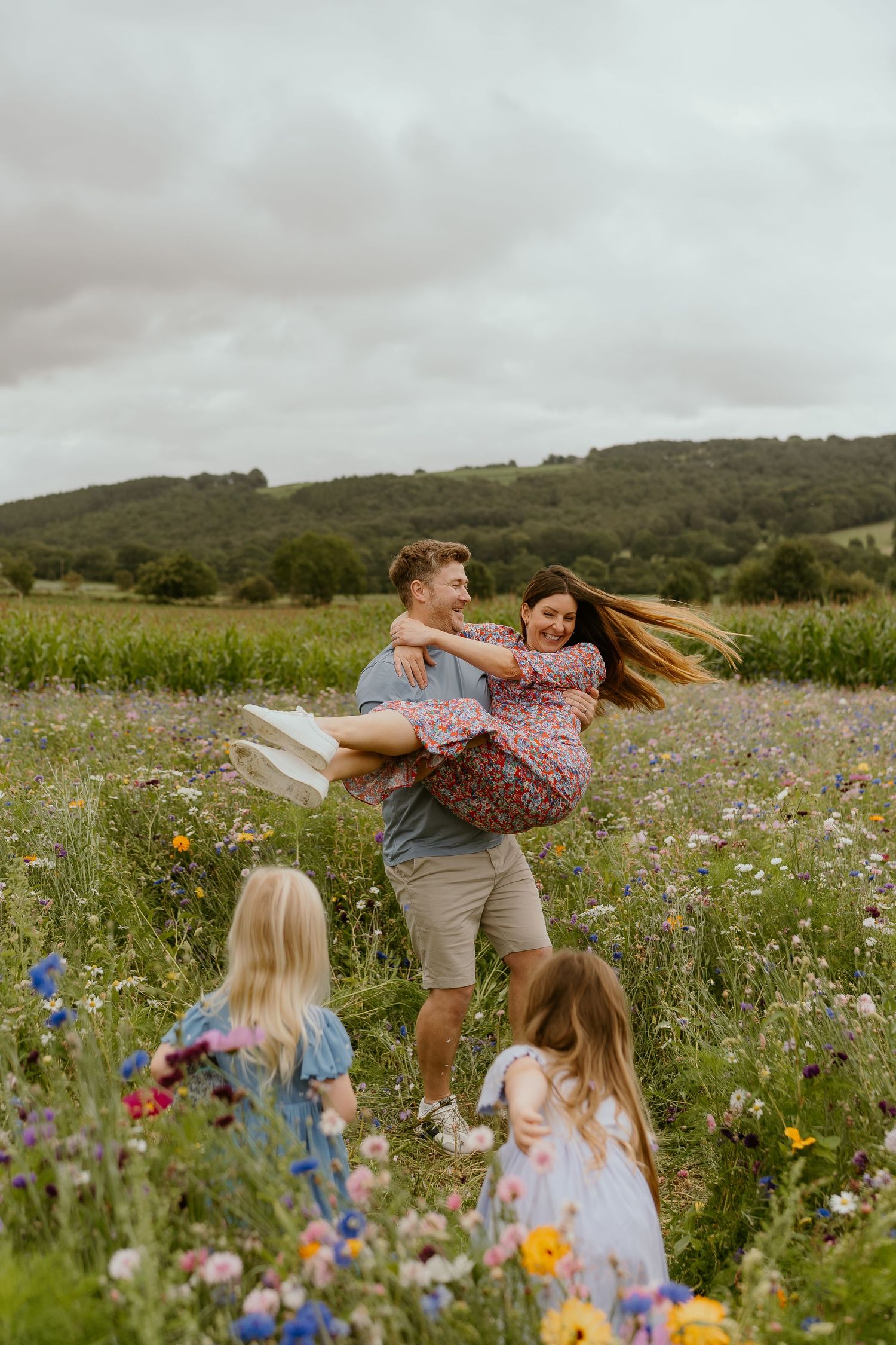 A playful family moment captured in a wildflower meadow with colorful blooms under cloudy skies in Harrogate.