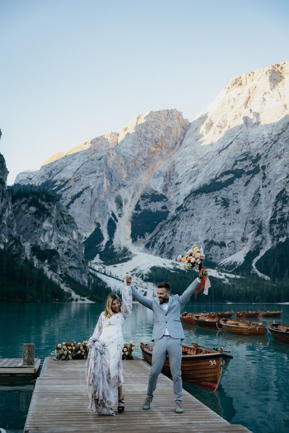 Celebratory moment on a wooden dock overlooking a pristine alpine lake and mountain range.