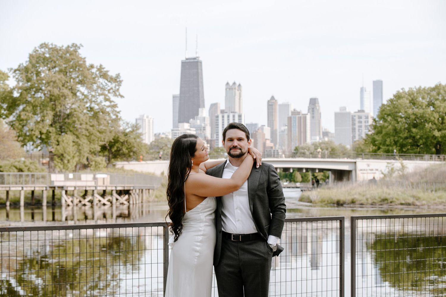 A couple shares a sweet moment by Lincoln Park pond with Chicago's iconic skyline in the background.