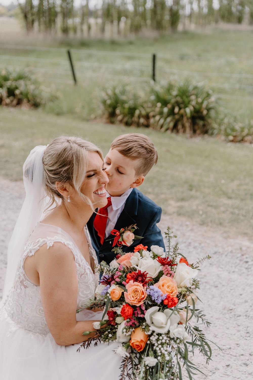 A couple shares a joyful moment with a vibrant autumn-toned wedding bouquet featuring roses and mixed flowers.
