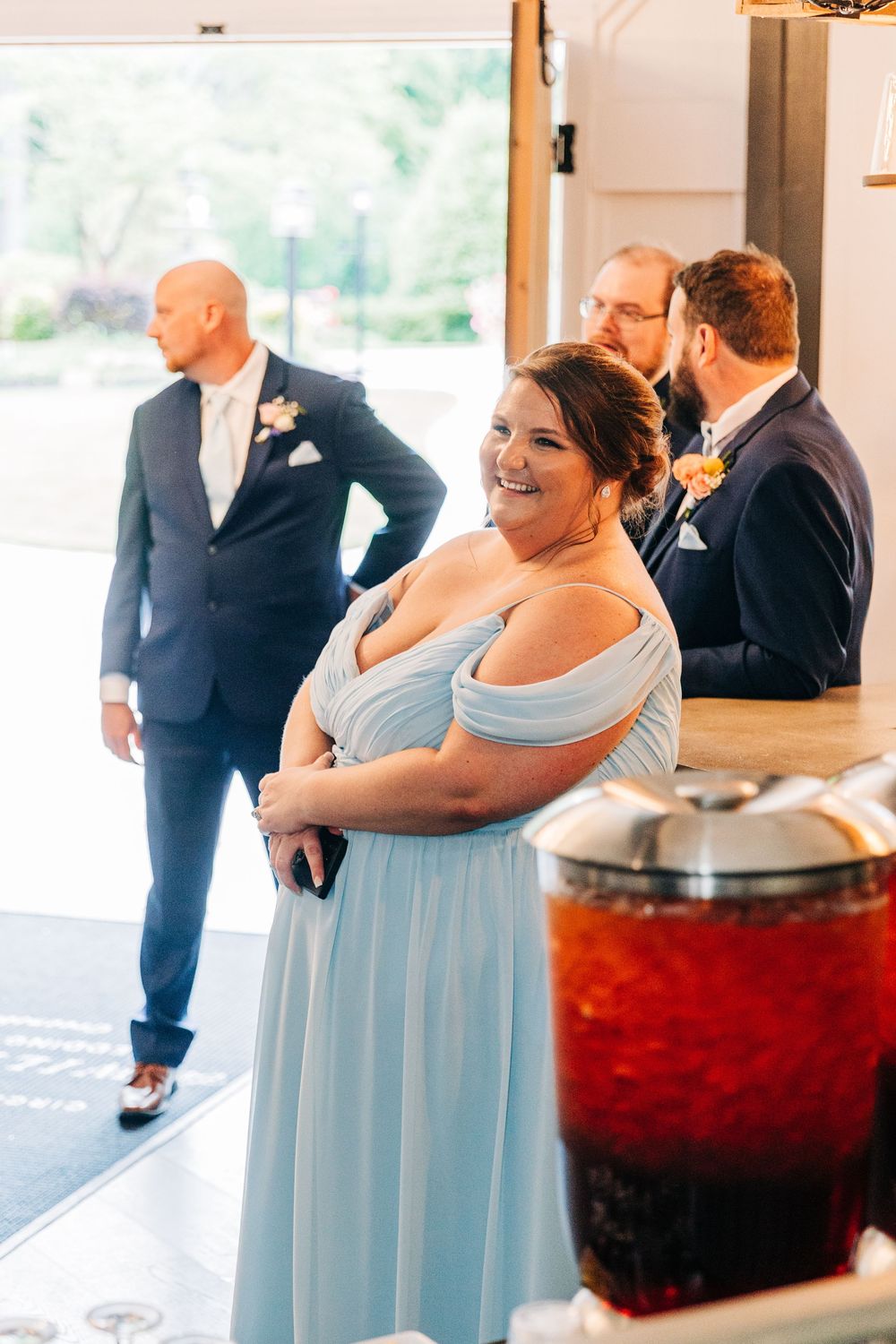 Bridesmaids in light blue dresses smile and celebrate during wedding reception.