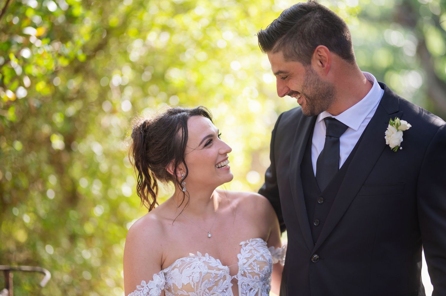 A romantic moment between newlyweds surrounded by lush greenery on their wedding day.