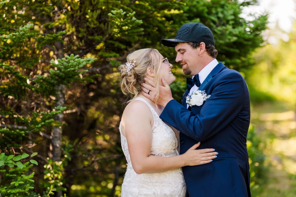 A romantic wedding moment captured outdoors with trees and natural sunlight in the background.