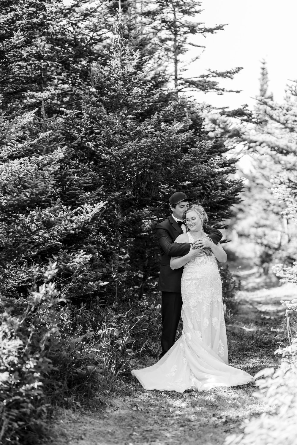 A romantic wedding photo sequence shows a couple embracing among evergreen trees in a forest setting.