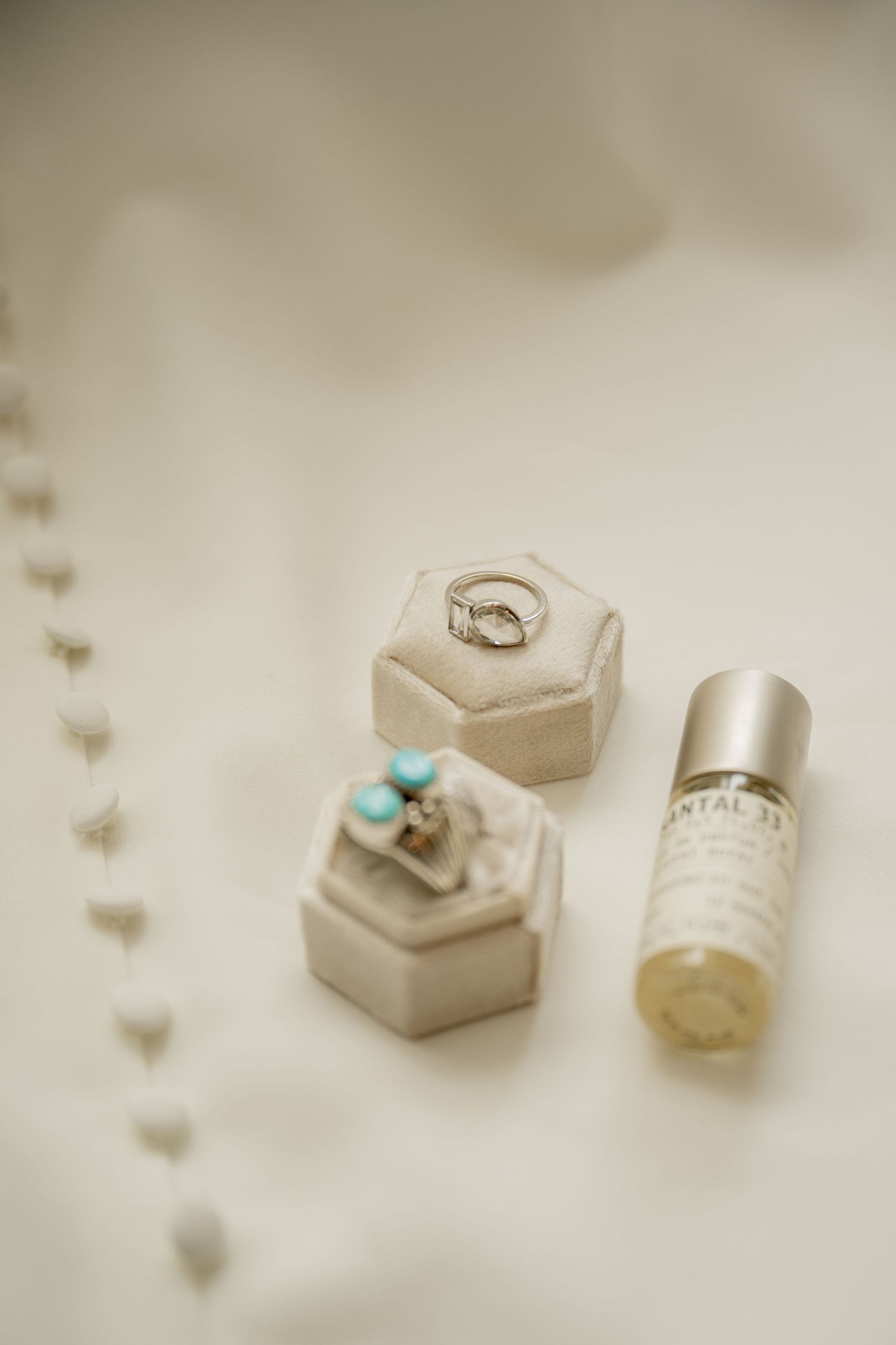 Small hexagonal crystal ring boxes and a shimmering glass vial arranged in a dreamy light setting.