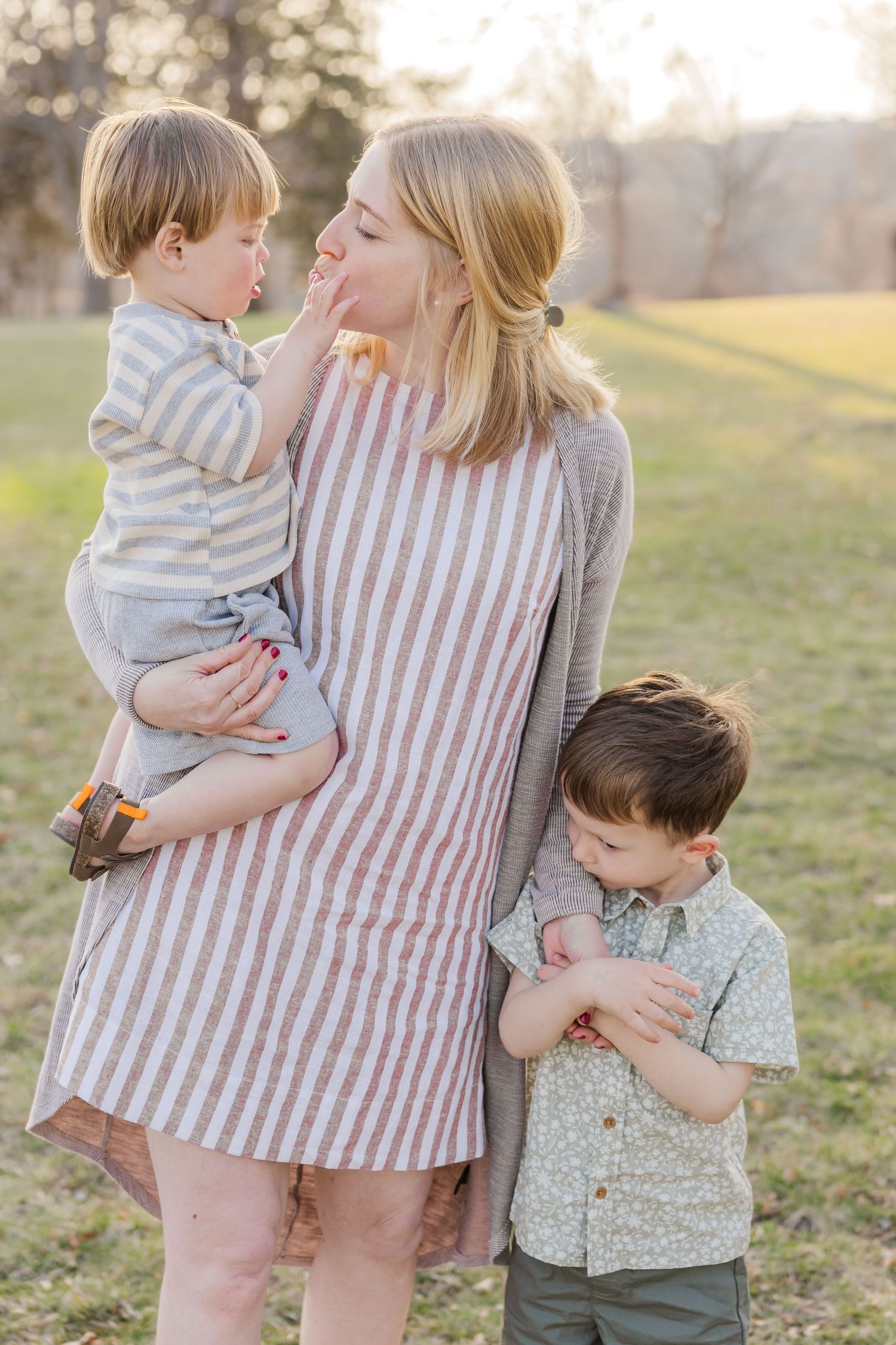 Family sharing a tender moment together outdoors in soft evening light. Family session.