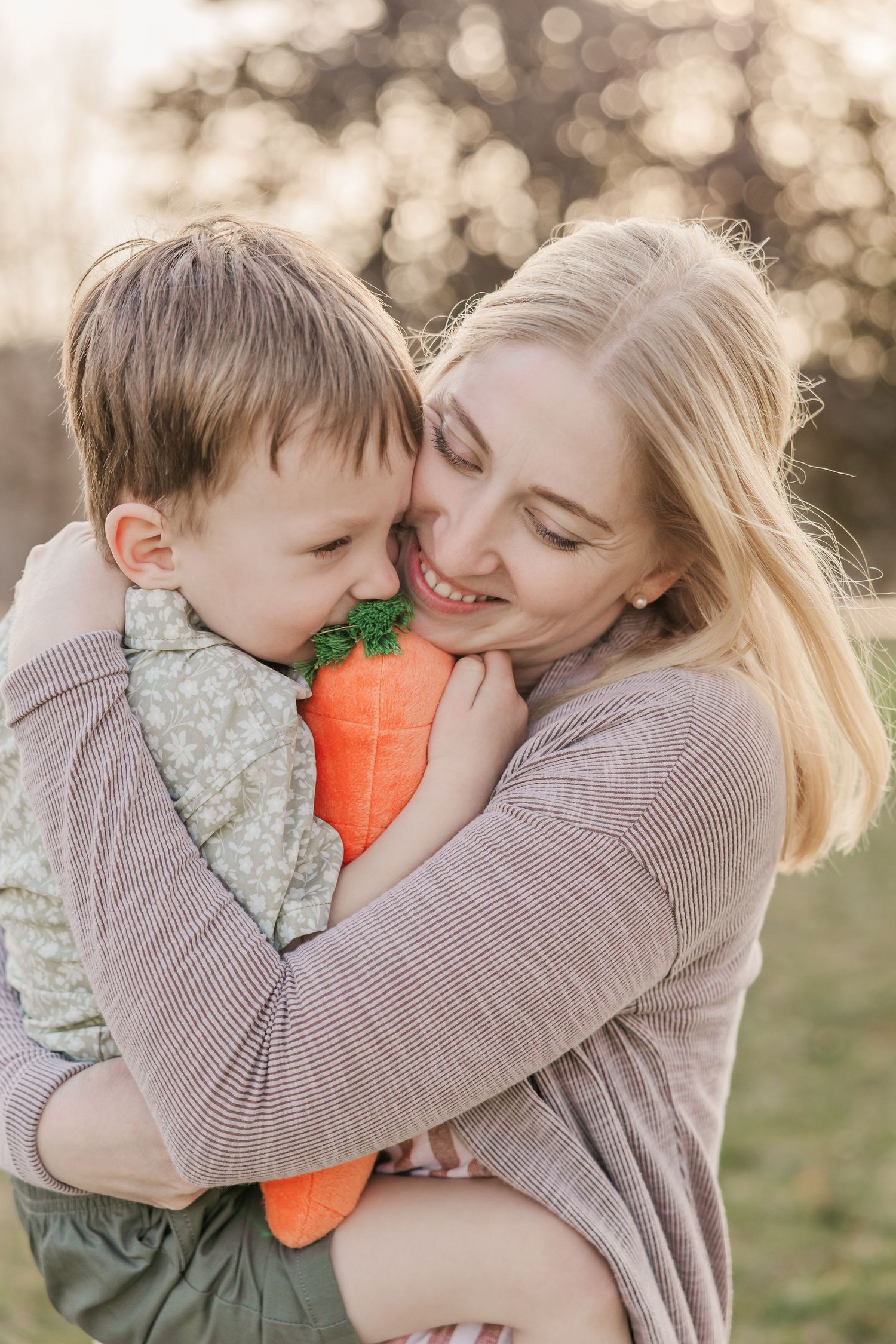 Sweet embrace with plush carrot toy during golden hour in park setting. Family photography