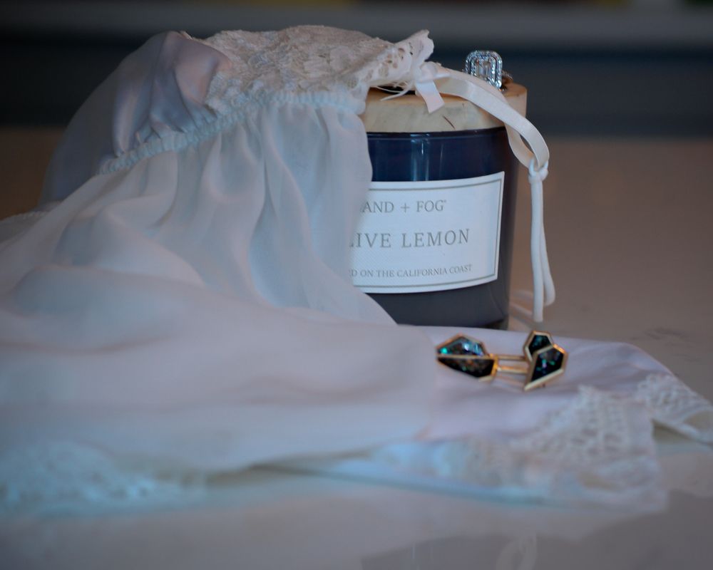 Olive Lemon candle jar wrapped in white fabric with small decorative accessories. Product photography, San Diego, California