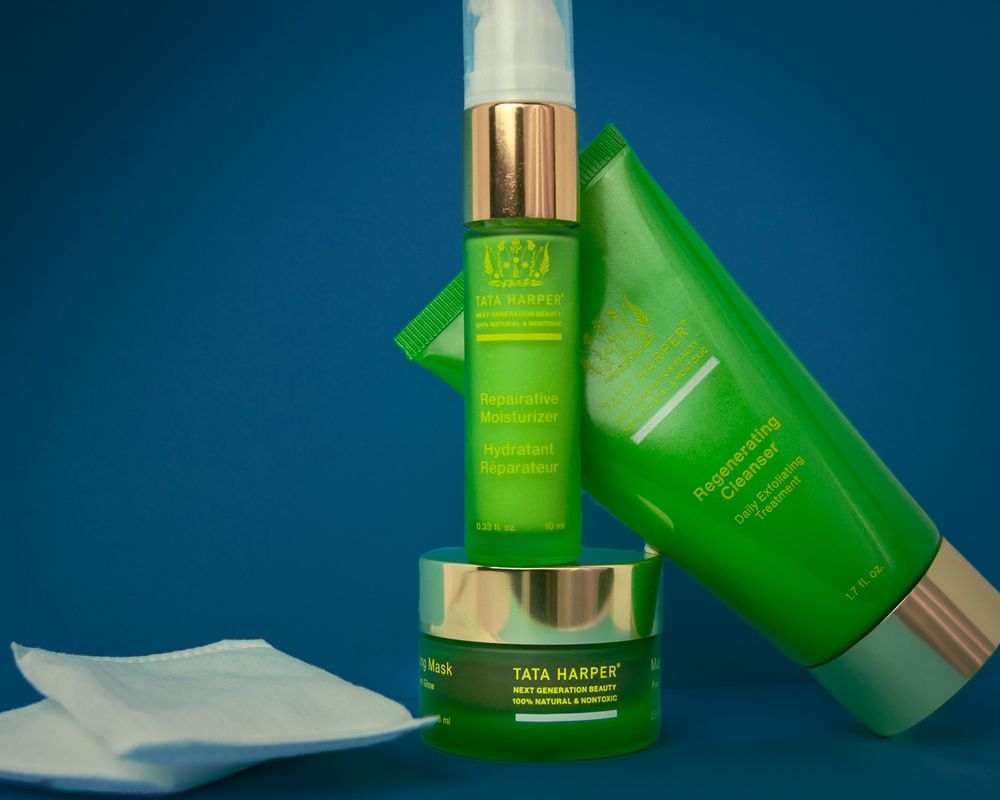 Green skincare products including serums and creams arranged against a blue background. Product photography, San Diego, California