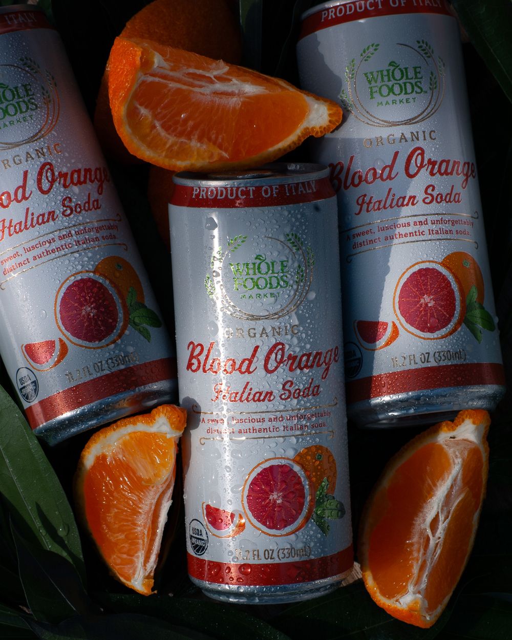 Whole Foods blood orange Italian soda cans arranged with fresh orange slices. Product photography, San Diego, California