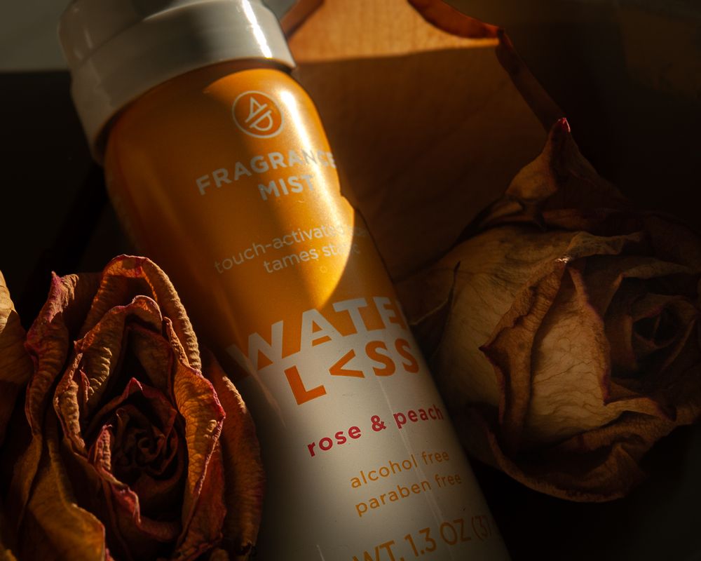 Orange fragrance bottle with dried roses photographed in dim atmospheric lighting. Product photography, San Diego, California