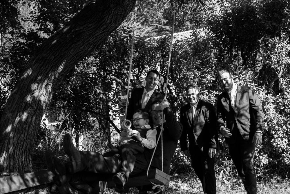 Black and white artistic photo of wedding party under tree canopy.