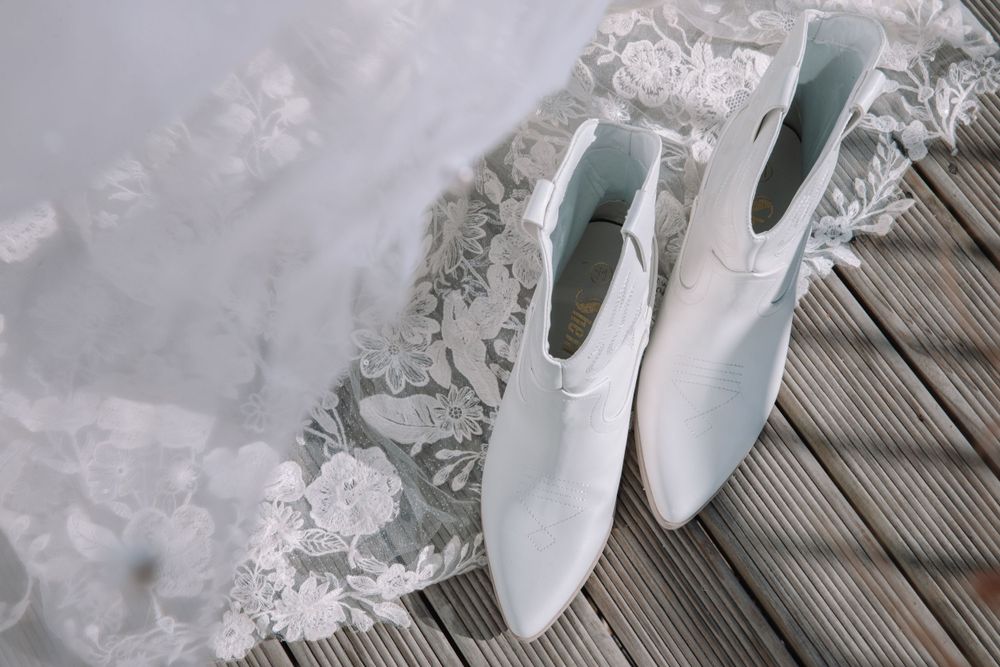 White bridal boots displayed next to delicate lace fabric.