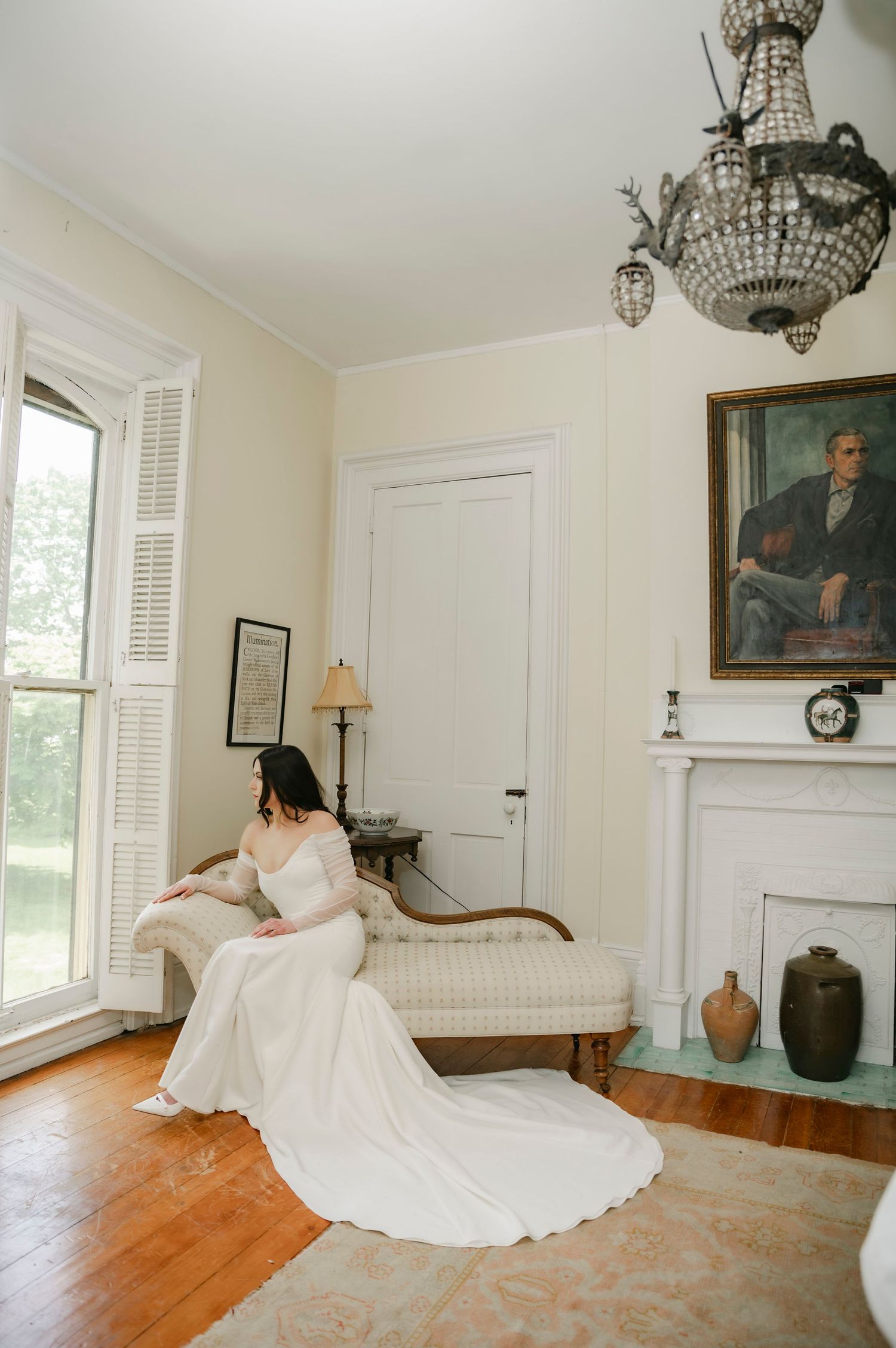 Bride in lace gown looking out window before wedding at Village View Farm, Lexington KY, captured in moody fine art style.