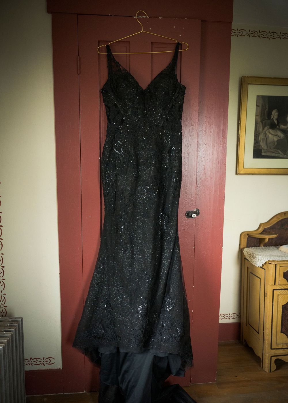 A progression of dark shadows cast on pink walls with a black evening gown hanging in the foreground.