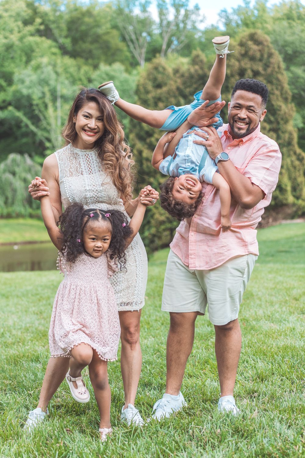 Playful family photoshoot with coordinated outfits showing joyful interactions on grass.