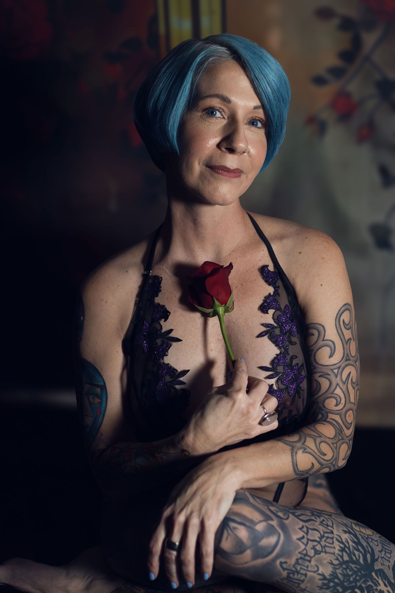 Tattooed woman holding rose in empowering session with one of the best boudoir photographers in Fort Worth.
