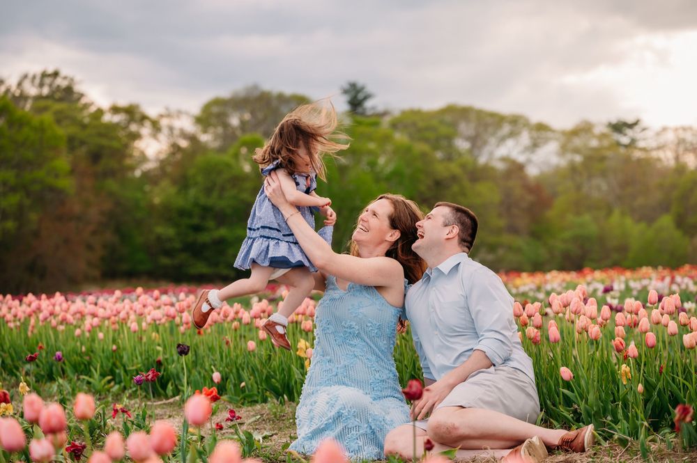 A family shares a joyful moment together in a blooming pink tulip field at sunset.