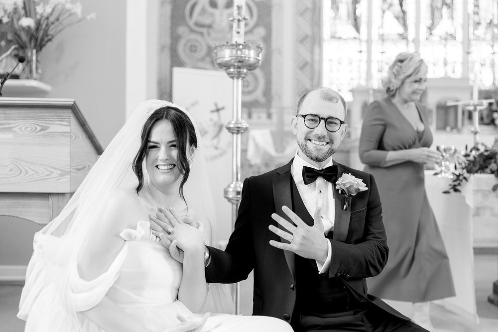 A happy couple celebrates during their wedding ceremony in a church with elegant decor and stained glass windows.